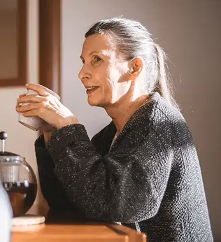 Photo of a woman in a charcoal knit holding a cup