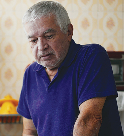 Photo of a man in a royal blue polo standing in his kitchen