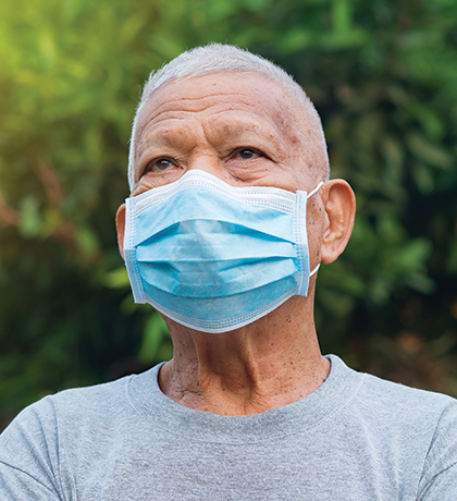 Photo of a man outdoors wearing a blue face mask