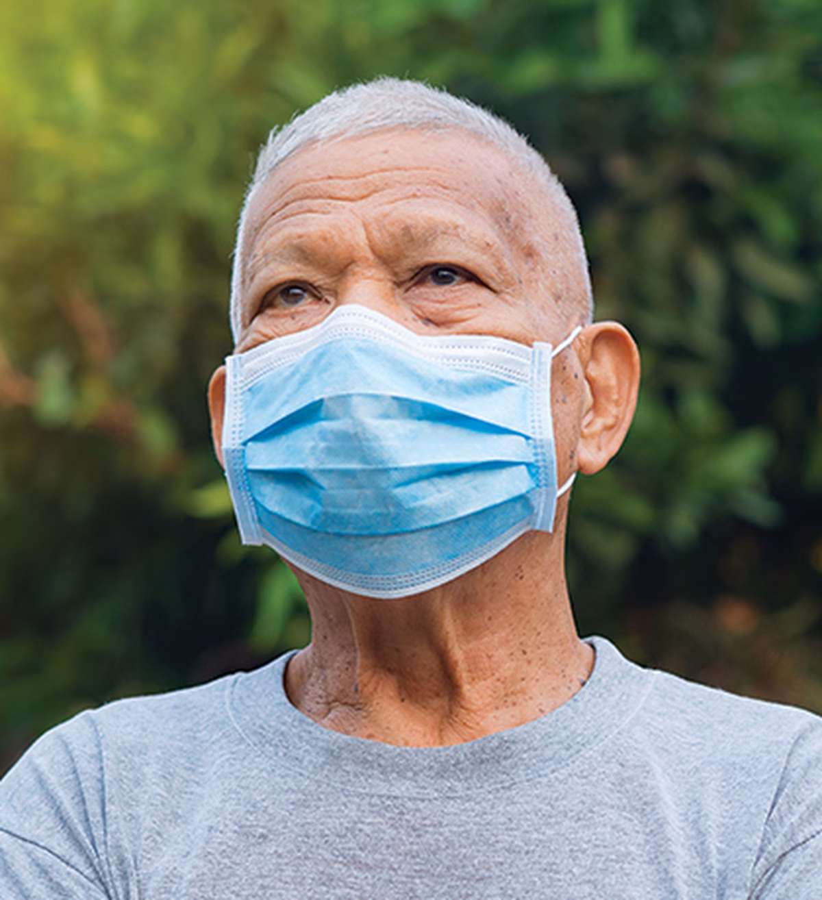Photo of a man outdoors wearing a blue face mask