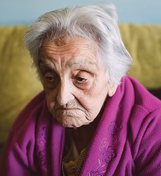 Photo of a glum older lady in a magenta dressing gown