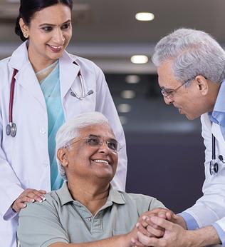 Photo of two doctors greeting a man in a wheelchair
