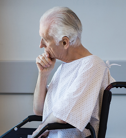 Photo of a man in a hospital gown in wheelchair