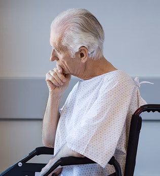 Photo of a man in a hospital gown in wheelchair