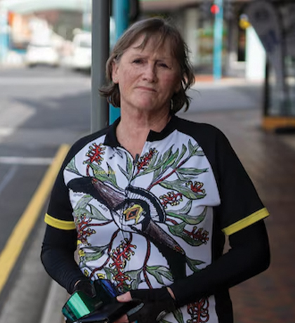 Photo of a woman in cycling gear standing by a city street