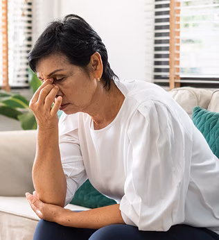 Photo of a seated woman pinching the bridge of her nose