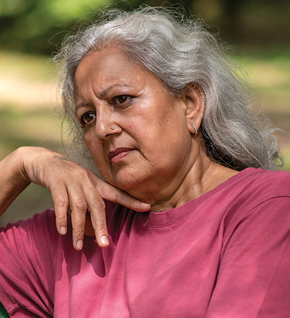 Photo of a woman in a raspberry t-shirt sitting on a green park bench