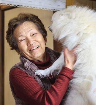 Photo of a smiling woman and a fluffy cream dog