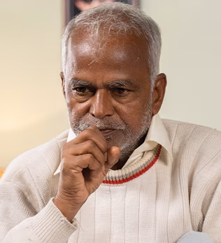 Photo of a man with his hand to his mouth in a well lit room