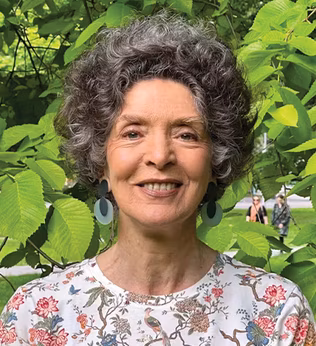 Photo of woman standing in front of lush greenery