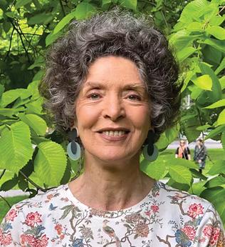 Photo of woman standing in front of lush greenery