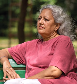 Photo of a woman in a red t shirt sitting on a park bench