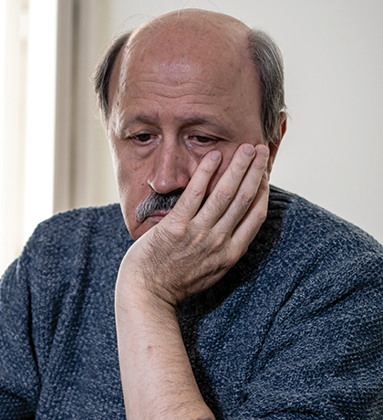 Photo of a balding man with his chin in his palm