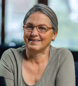 Photo of a woman in a sage green top sitting on a blue couch