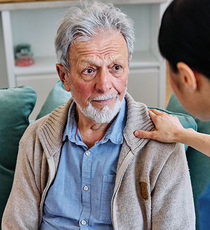 Photo of a health worker's hand on a man's shoulder