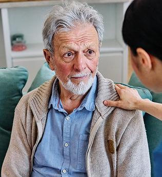 Photo of a health worker's hand on a man's shoulder