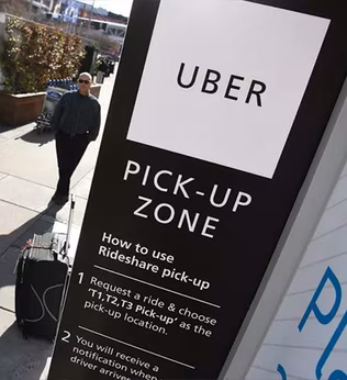 Photo of Uber pickup sign on a street with suitcases and a waiting man