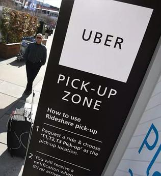 Photo of Uber pickup sign on a street with suitcases and a waiting man