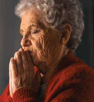 Photo of a woman praying in a red cardigan