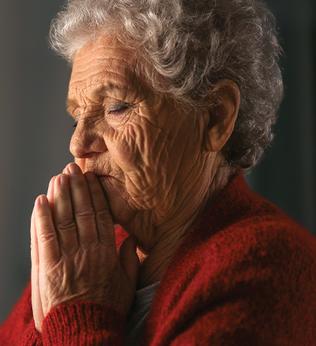 Photo of a woman praying in a red cardigan