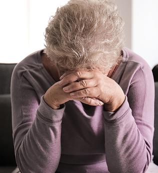 Photo of a woman in a lilac top resting her head on her hands