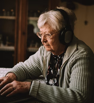 Photo of a woman sitting at a laptop wearing headphones
