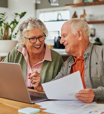 Photo of a smiling couple sitting at their laptop