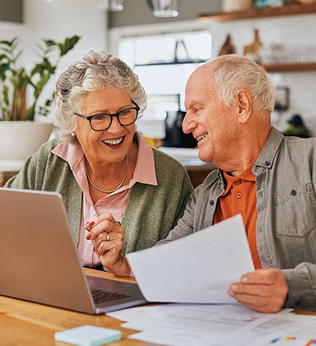 Photo of a smiling couple sitting at their laptop