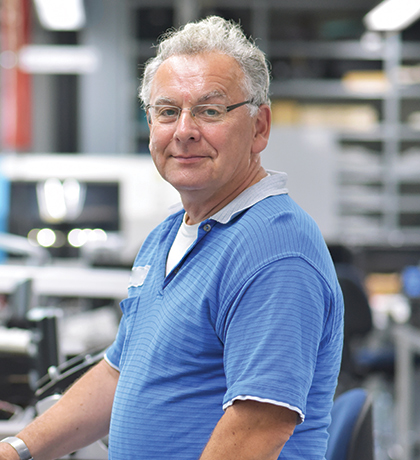 Photo of a man in a blue polo standing at a warehouse computer desk