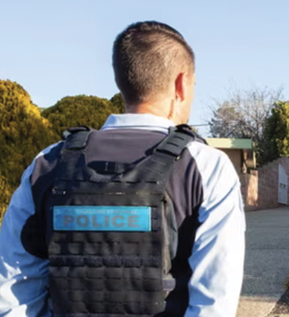 Photo of a police officer standing in front of a cream brick home