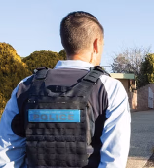 Photo of a police officer standing in front of a cream brick home
