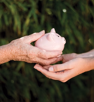 Photo of older hands giving piggy bank to younger hands