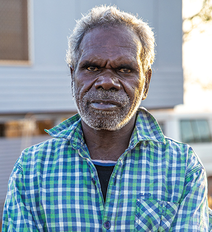 Photo of a man standing in front of a home on stilts