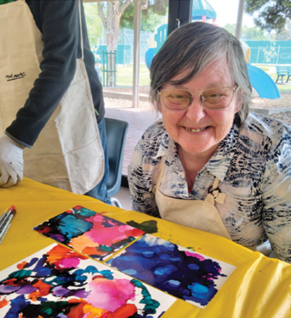 Photo of a smiling woman and her painting