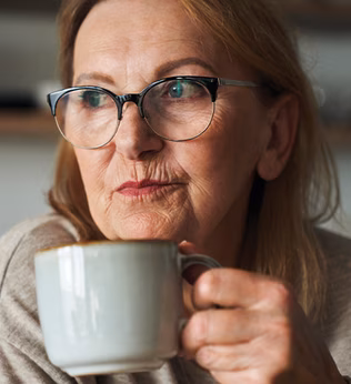 Photo of a woman holding a coffee cup and wearing glasses