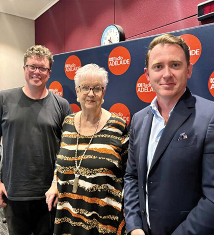 Photo of three people standing in front of an ABC Radio banner