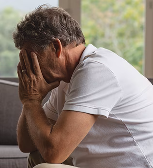 Photo of a man sitting on a couch with head in hands