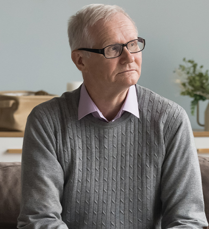 Photo of a pensive man sitting on a comfortable sofa