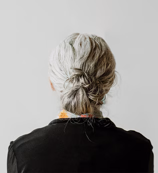 Photo of the back of a woman's head with her hair tied in a grey bun