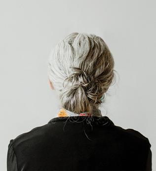 Photo of the back of a woman's head with her hair tied in a grey bun
