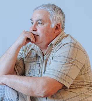 Photo of a man in a cream plaid shirt sitting on a sofa