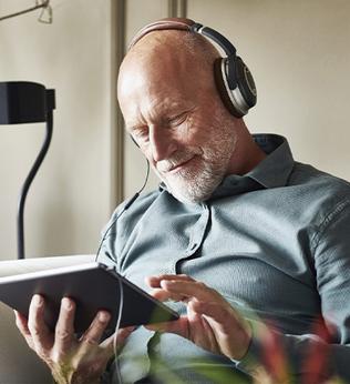 Image of an older man listening to a podcast