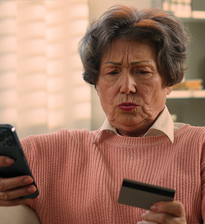 Photo of a concerned woman looking at her phone and credit card