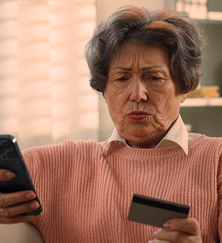 Photo of a concerned woman looking at her phone and credit card