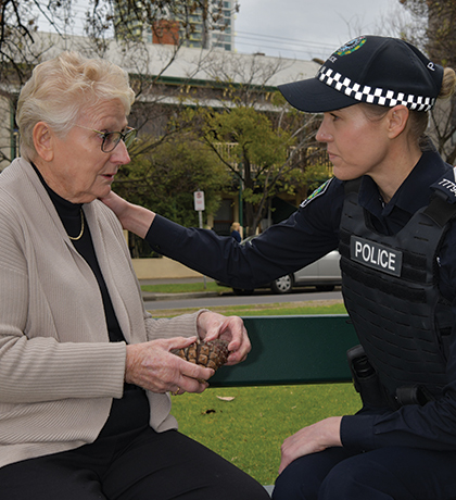 Photo of police officer comforting a woman on a park bench