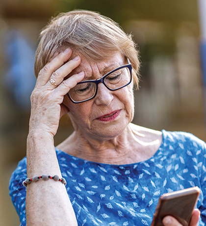 Photo of a woman in blue top looking at her mobile phone