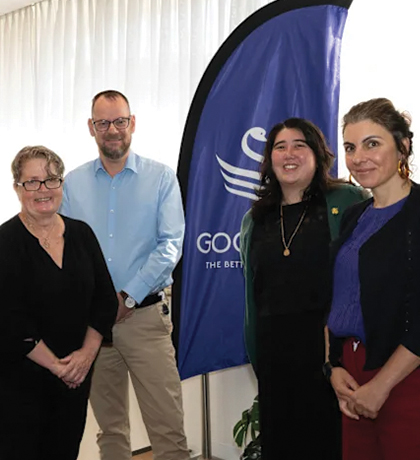 Photo of four smiling people standing next to banners