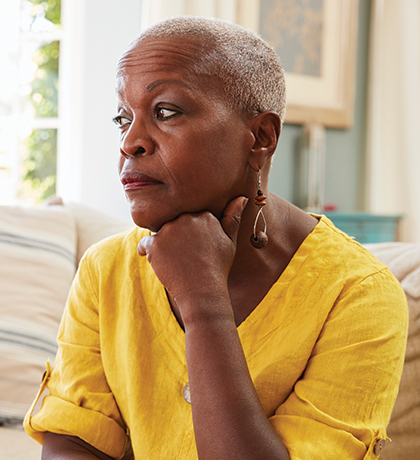 Photo of a woman in a yellow top resting her chin on her hand