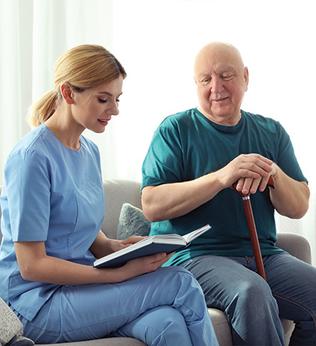 Photo of health professional reading a book next to an older man