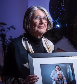 Photo of a woman in a darkened room holding a framed portrait